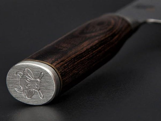 KAI Shun Premier Tim Mälzer Santoku mit 18 cm Klinge. VG-MAX Stahlkern (61 HRC), 32 Lagen Damast, hochglanzpoliert mit Hammerschlagoberfläche. Griff aus gemasertem Pakkaholz in Mittelbraun. Das Präzisionswerkzeug aus Japan.