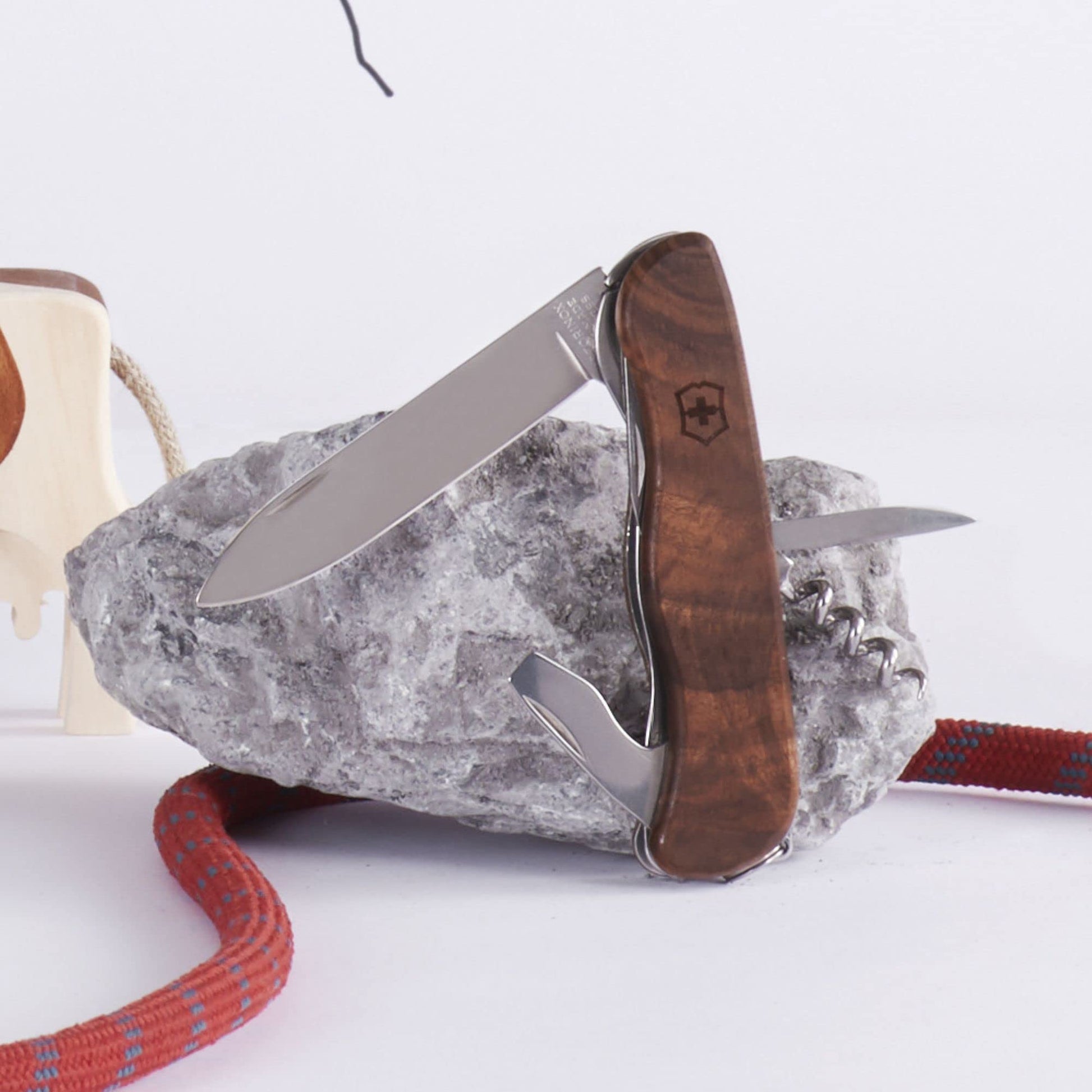 Victorinox Forester Wood mit geöffneten Klingen vor Stein liegend– original Schweizer Taschenmesser mit Walnussholzgriff