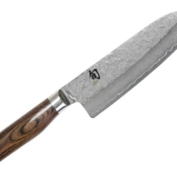 KAI Shun Premier Tim Mälzer Santoku mit 18 cm Klinge – VG-MAX Stahlkern (61 HRC), 32 Lagen Damast, hochglanzpoliert mit Hammerschlagoberfläche. Griff aus gemasertem Pakkaholz in Mittelbraun. Präzisionswerkzeug aus Japan für stilvolles Schneiden.